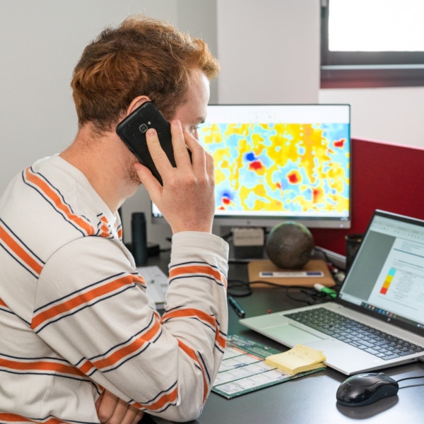 Homme au téléphone assis devant un bureau sur lequel repose un ordinateur ouvert - Navarra TS